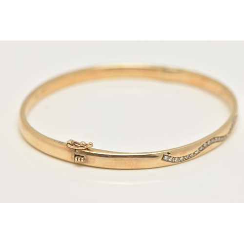 49 - A 9CT GOLD DIAMOND SET HINGED BANGLE, of a polished design, set with a wavy row of small round brill... 