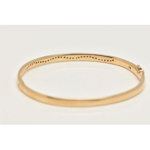 49 - A 9CT GOLD DIAMOND SET HINGED BANGLE, of a polished design, set with a wavy row of small round brill... 