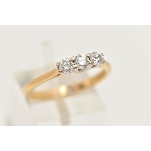 60 - A YELLOW METAL DIAMOND THREE STONE RING, set with three round brilliant cut diamonds, shared four cl... 