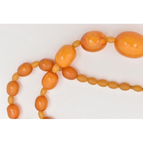 63 - A BAKELITE BEAD NECKLACE, oval orange beads graduating in size with small beads interspaced with sma... 