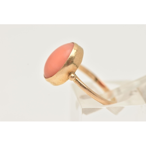 74 - A YELLOW METAL CORAL RING, designed with an oval coral cabochon, in a collet setting, measuring appr... 