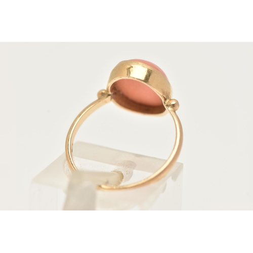 74 - A YELLOW METAL CORAL RING, designed with an oval coral cabochon, in a collet setting, measuring appr... 