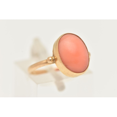 74 - A YELLOW METAL CORAL RING, designed with an oval coral cabochon, in a collet setting, measuring appr... 