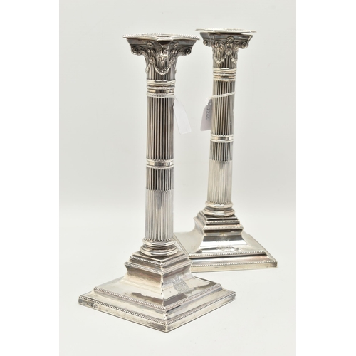 120 - A PAIR OF PRESENTATION CANDLESTICKS, Corinthian columns, scrolling and swag detail beneath the drip ... 