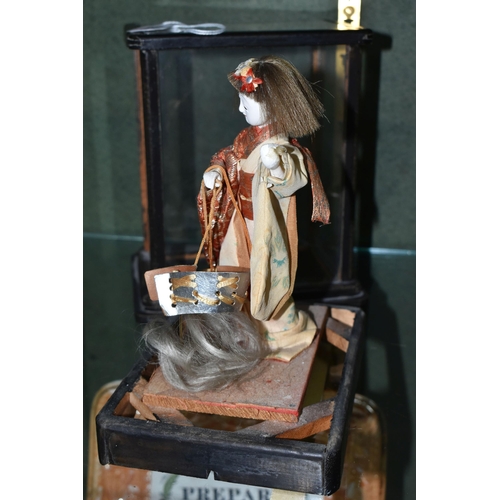 358 - A JAPANESE COSTUME DOLL IN A GLAZED CASE, the vintage female doll wearing a kimono and holding a sam... 