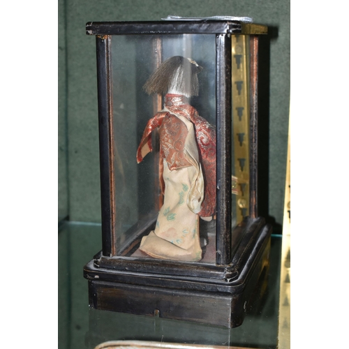 358 - A JAPANESE COSTUME DOLL IN A GLAZED CASE, the vintage female doll wearing a kimono and holding a sam... 