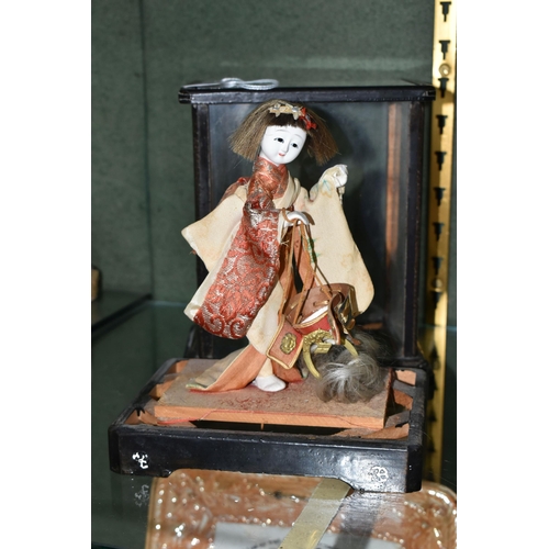 358 - A JAPANESE COSTUME DOLL IN A GLAZED CASE, the vintage female doll wearing a kimono and holding a sam... 