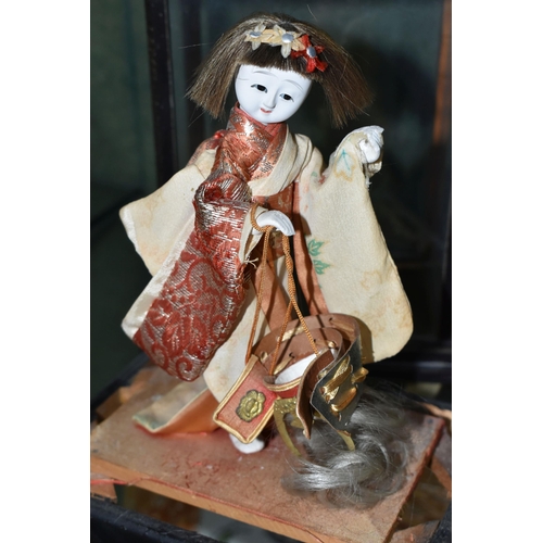 358 - A JAPANESE COSTUME DOLL IN A GLAZED CASE, the vintage female doll wearing a kimono and holding a sam... 