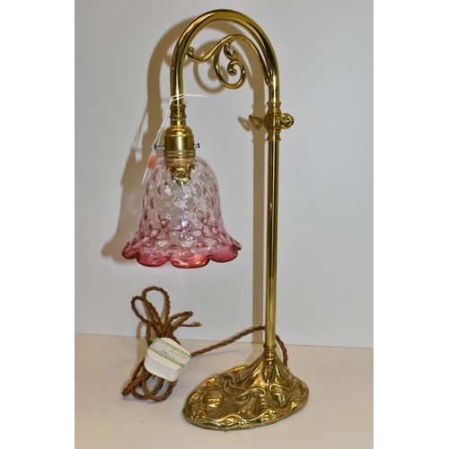 492 - A BRASS TABLE/DESK LAMP, in art nouveau style, with foliate scroll under arched neck, cast floral de... 