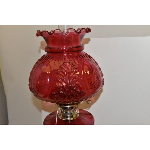 494 - A VICTORIAN STYLE CRANBERRY COLOURED GLASS OIL LAMP, with circular silver coloured Corinthian column... 