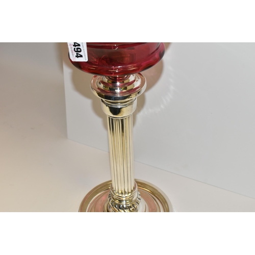 494 - A VICTORIAN STYLE CRANBERRY COLOURED GLASS OIL LAMP, with circular silver coloured Corinthian column... 