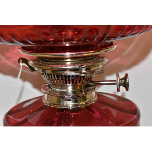 494 - A VICTORIAN STYLE CRANBERRY COLOURED GLASS OIL LAMP, with circular silver coloured Corinthian column... 