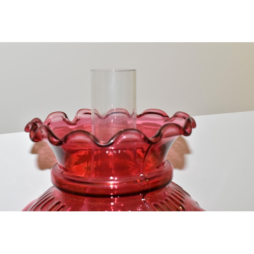 494 - A VICTORIAN STYLE CRANBERRY COLOURED GLASS OIL LAMP, with circular silver coloured Corinthian column... 