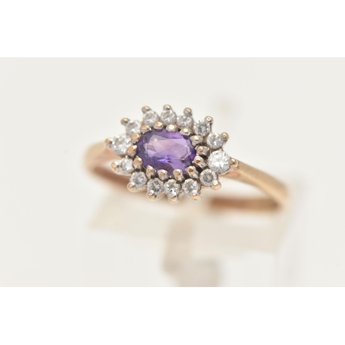 84 - A 9CT YELLOW GOLD AMETHYST CLUSTER RING, of an oval form, set to the centre with an oval cut amethys... 