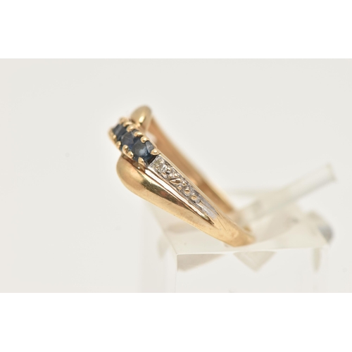 89 - A 9CT GOLD GEM SET RING, of a cross over design, set with a row of four circular cut deep blue sapph... 