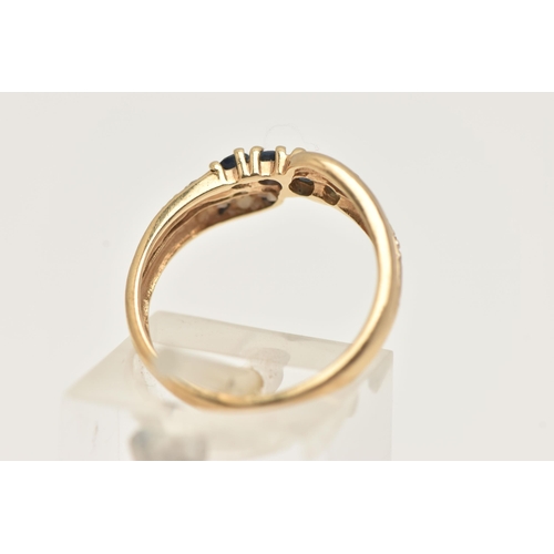 89 - A 9CT GOLD GEM SET RING, of a cross over design, set with a row of four circular cut deep blue sapph... 