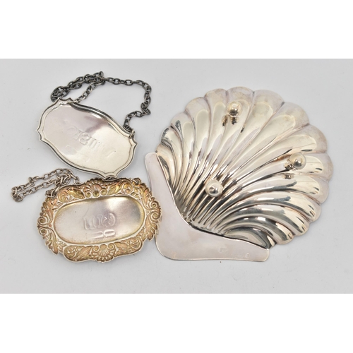 170 - A SILVER SHELL SHAPE DISH AND TWO DECANTER LABELS, the shell shape dish raised on three ball feet, h... 