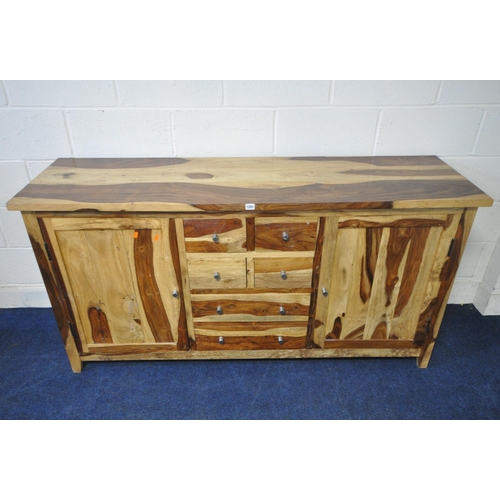 1201 - A MANGO WOOD SIDEBOARD, fitted with an arrangement of six drawers, flanked by two cupboard doors, le... 