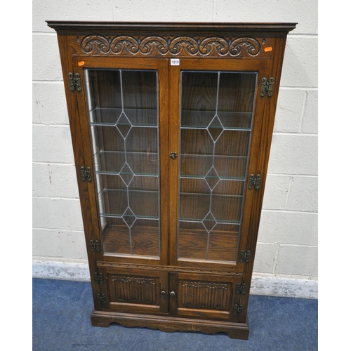 1219 - AN OLD CHARM OAK DISPLAY CABINET, the double lead glazed doors enclosing three glass shelves, above ... 