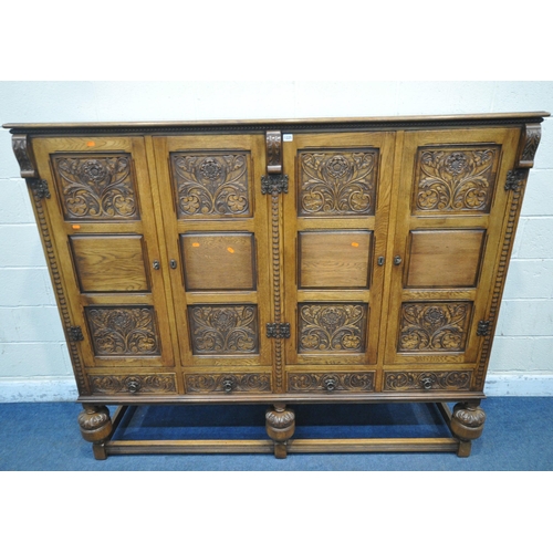 1225 - A 20TH CENTURY SOLID OAK FOUR DOOR CUPBOARD, each door with two panels depicting the Tudor rose, abo... 