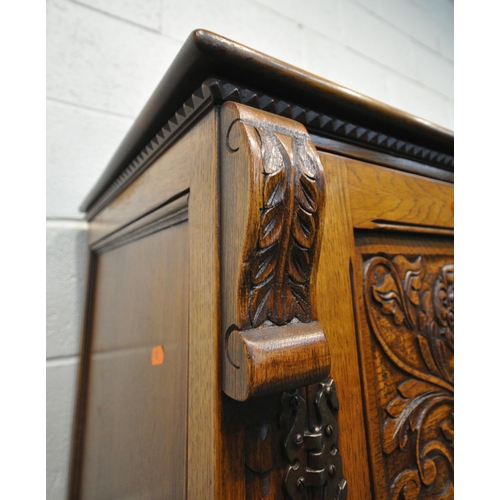 1225 - A 20TH CENTURY SOLID OAK FOUR DOOR CUPBOARD, each door with two panels depicting the Tudor rose, abo... 