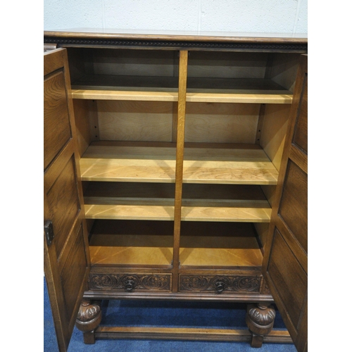 1225 - A 20TH CENTURY SOLID OAK FOUR DOOR CUPBOARD, each door with two panels depicting the Tudor rose, abo... 