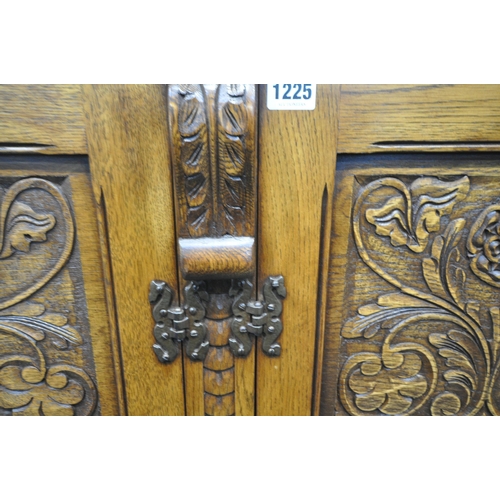 1225 - A 20TH CENTURY SOLID OAK FOUR DOOR CUPBOARD, each door with two panels depicting the Tudor rose, abo... 