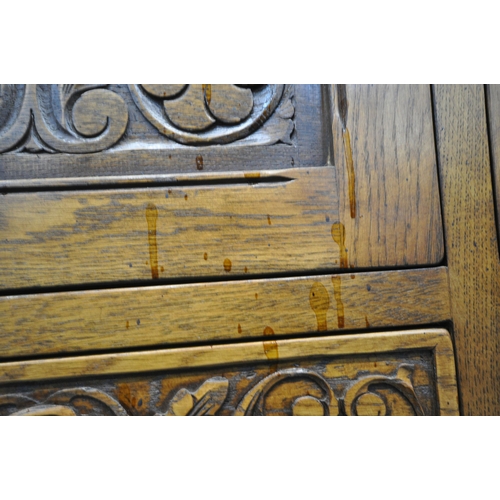 1225 - A 20TH CENTURY SOLID OAK FOUR DOOR CUPBOARD, each door with two panels depicting the Tudor rose, abo... 