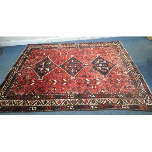 1259 - A LARGE RED IRANIAN WOOLEN RUG, with repeating geometric patterns, surrounded by a multi-strap borde... 