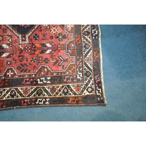 1259 - A LARGE RED IRANIAN WOOLEN RUG, with repeating geometric patterns, surrounded by a multi-strap borde... 