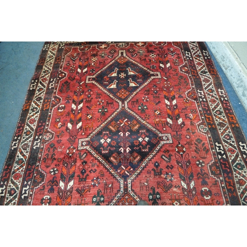 1259 - A LARGE RED IRANIAN WOOLEN RUG, with repeating geometric patterns, surrounded by a multi-strap borde... 