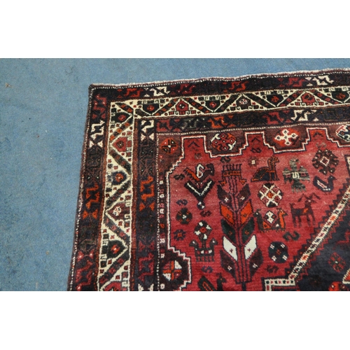 1259 - A LARGE RED IRANIAN WOOLEN RUG, with repeating geometric patterns, surrounded by a multi-strap borde... 