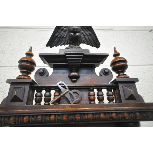 1261 - A 20TH CENTURY OAK WALL CLOCK, eagle pediment, flanked by twin finials, the door enclosing a 7 inch ... 