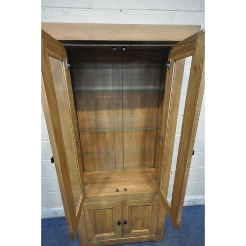 1269 - A MODERN SOLID OAK BOOKCASE, fitted with double glazed doors, above double cupboard doors, width 94c... 