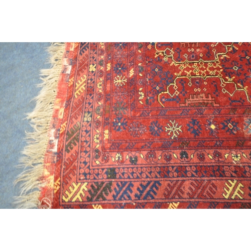 1280 - A RED GROUND RECTANGULAR WOOLEN RUG, with repeating geometric patterns, surrounded by a multi-strap ... 