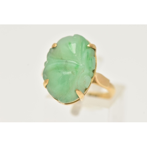 3 - A CARVED JADE RING, oval carved green jade, prong set in yellow metal, approximate length 18mm, yell... 