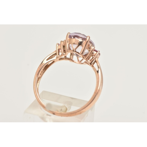 41 - A 9CT GOLD GEM SET RING, an oval cut pink stone, flanked with four round brilliant cut diamonds and ... 