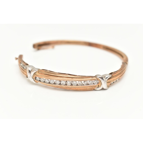 74 - A 9CT GOLD DIAMOND BANGLE, eighteen diamonds channel set in a bi colour hinged bangle, approximate t... 