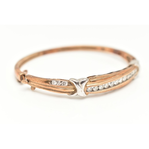 74 - A 9CT GOLD DIAMOND BANGLE, eighteen diamonds channel set in a bi colour hinged bangle, approximate t... 