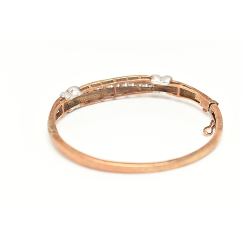 74 - A 9CT GOLD DIAMOND BANGLE, eighteen diamonds channel set in a bi colour hinged bangle, approximate t... 