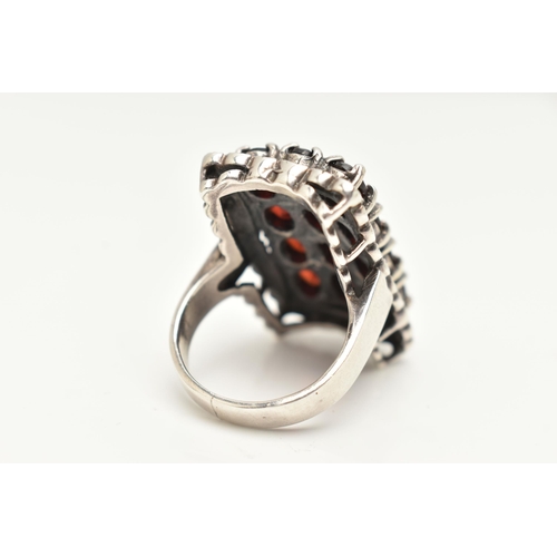 85 - A WHITE METAL GARNET SET DRESS RING, of a large rectangular form set with four rows of three oval cu... 