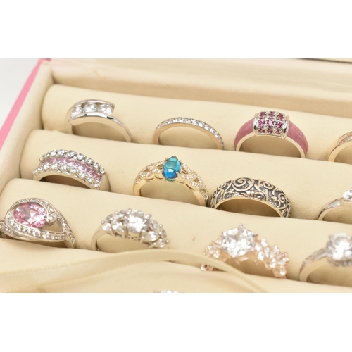 135 - A PINK RING STORAGE BOX WITH TWENTY WHITE METAL RINGS, of various designs, most set with cubic zirco... 