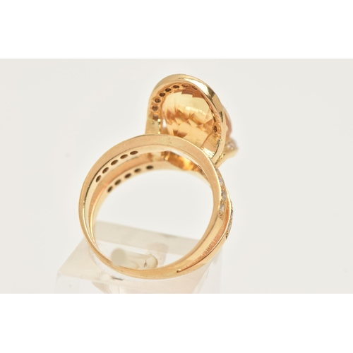 176 - A MODERN YELLOW METAL CITRINE AND DIAMOND DRESS RING, set with an oval shape fancy cut Citrine, meas... 