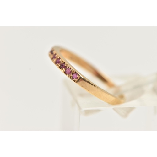 30 - A YELLOW METAL RUBY SET HALF ETERNITY RING, set with a row of nine small circular cut rubies, to a p... 