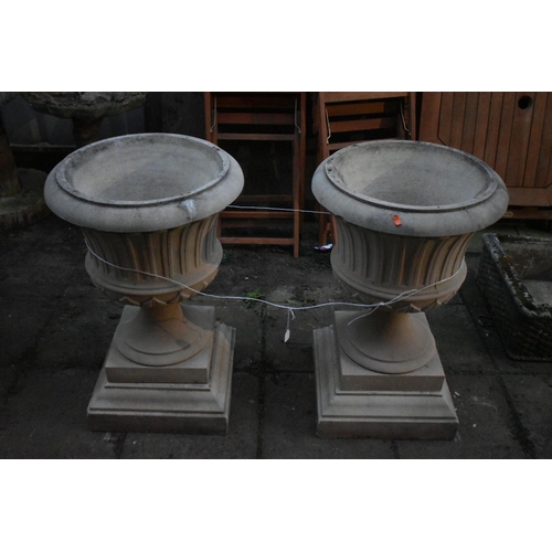 1011 - A PAIR OF PARTIALLY WEATHERED URNS, on a  separate square plinth, diameter 49cm x height 79cm (condi... 