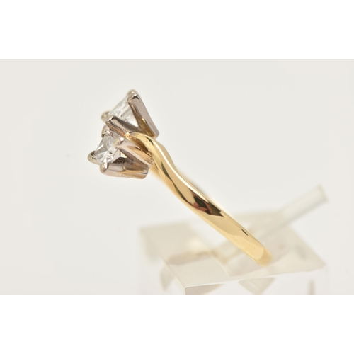 22 - AN 18CT GOLD DIAMOND CROSS OVER RING, designed as two princess cut diamonds each in a four claw sett... 