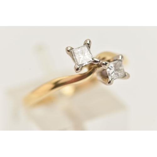 22 - AN 18CT GOLD DIAMOND CROSS OVER RING, designed as two princess cut diamonds each in a four claw sett... 