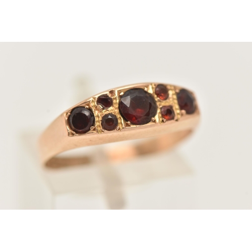 51 - A LATE VICTORIAN 15CT GOLD GARNET RING, set with seven circular cut garnets, to a polished band, hal... 