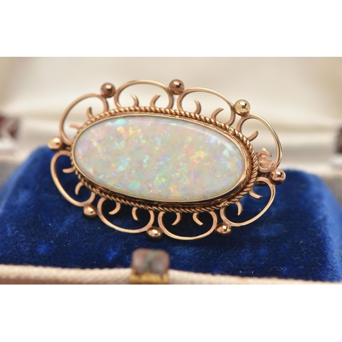 185 - A 9CT GOLD AND SYNTHETIC OPAL BROOCH, an oval synthetic opal, collet set with open work scrolling de... 