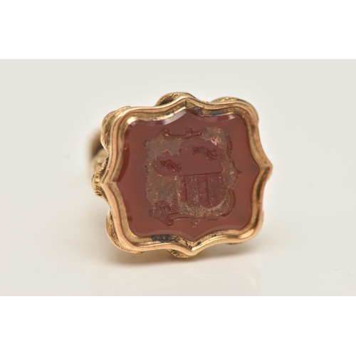 75 - A YELLOW METAL FOB SEAL, wavy form set with an intaglio carnelian inlay, depicting a coat of arms, t... 